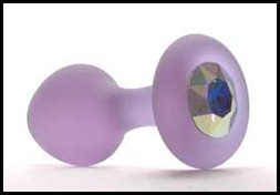 A Crystal Delights butt plug made of lavender frosted glass with a shiny glass crystal in the center of the base that is blue in the middle, but refracts yellow light on the facets.